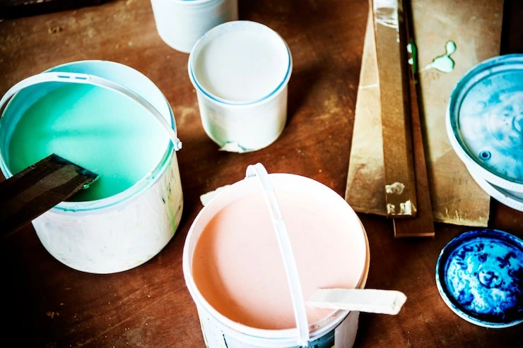 Open paint cans in multiple colors on a wooden surface representing paint coverage and home interior painting