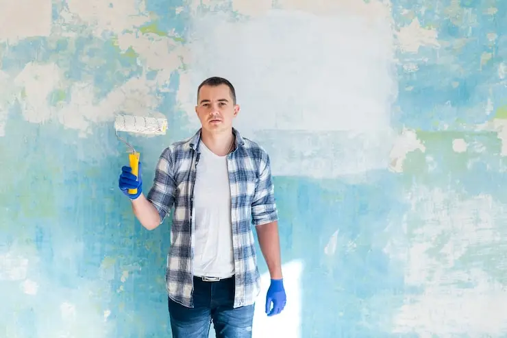 Man painting interior wall with roller — how often should I repaint my walls for a fresh look